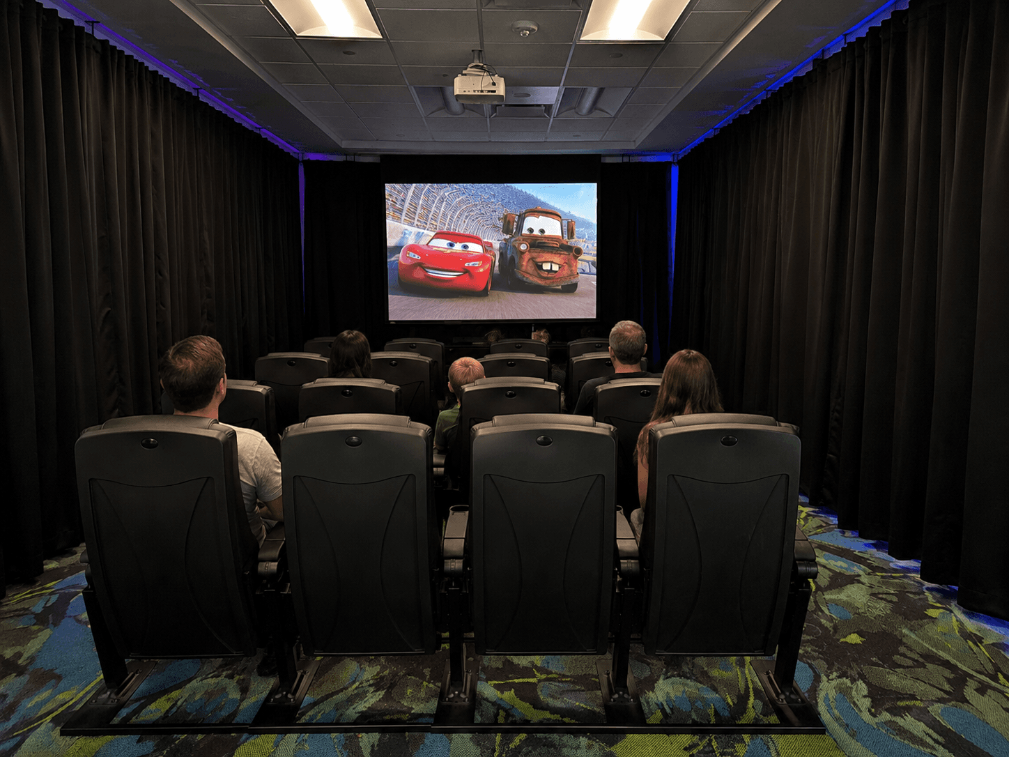 Families watching a movie in the THIScar movie theater waiting room